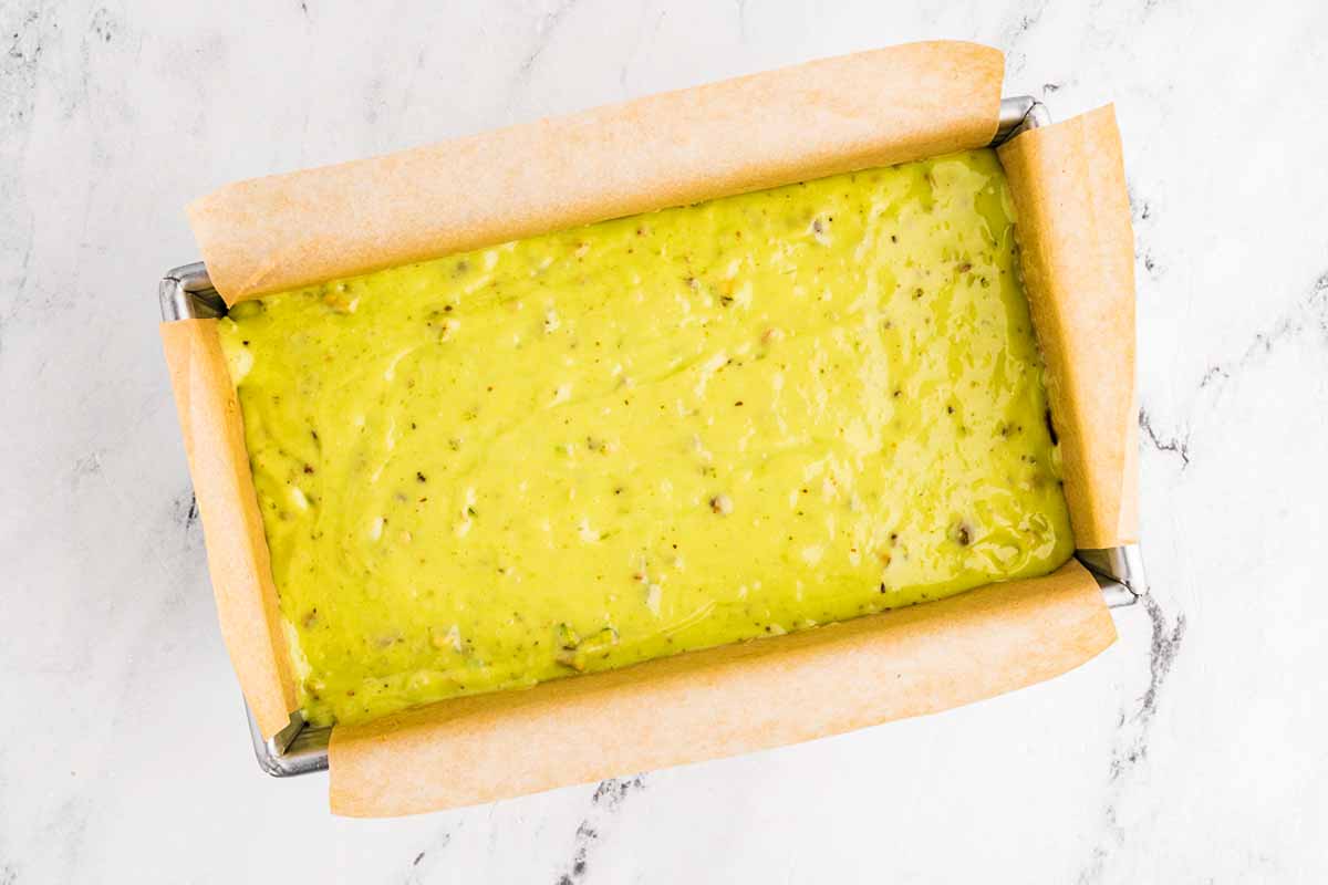 overhead view of pistachio bread batter spread in loaf pan