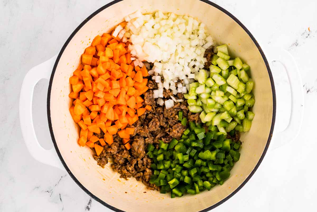 overhead view of browned sausage with diced aromatic vegetables in pot