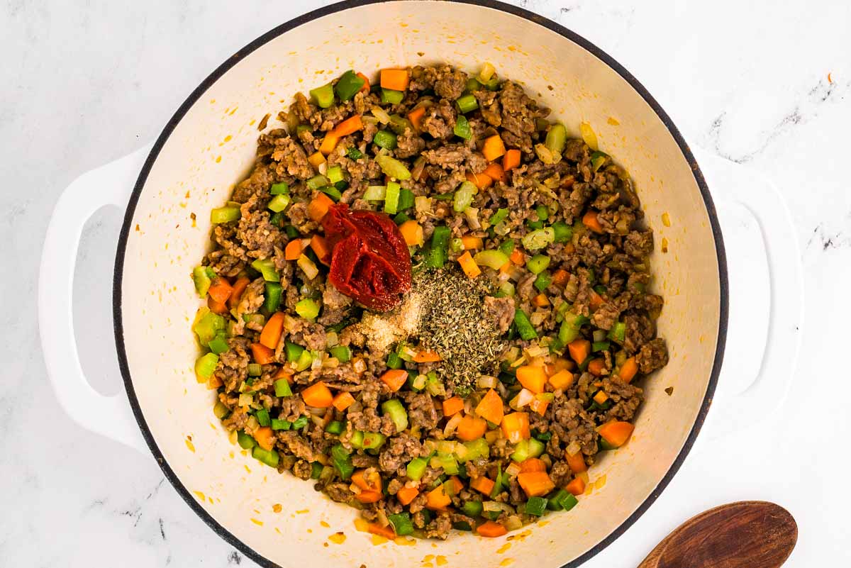 overhead view of browned sausage and sautéed vegetables in pot