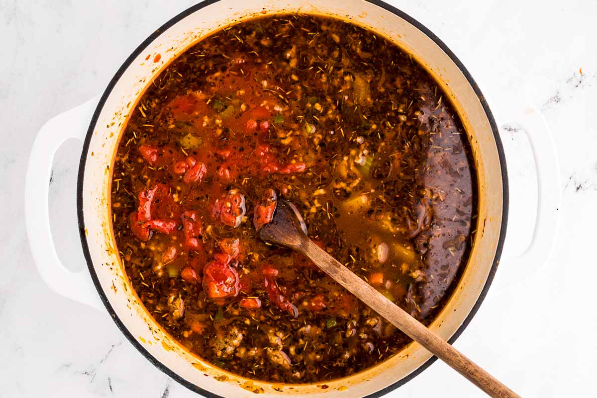 overhead view of vegetables and broth in pot with diced tomatoes