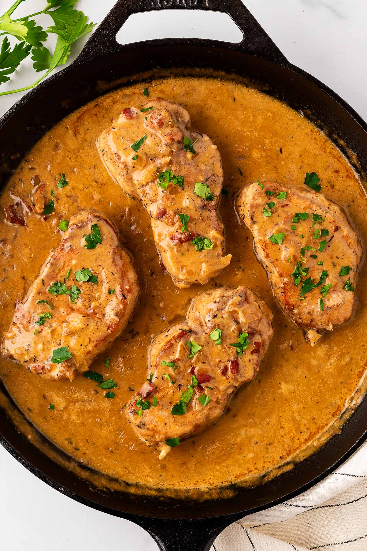 overhead view of four pork chops smothered in gravy in cast iron skillet