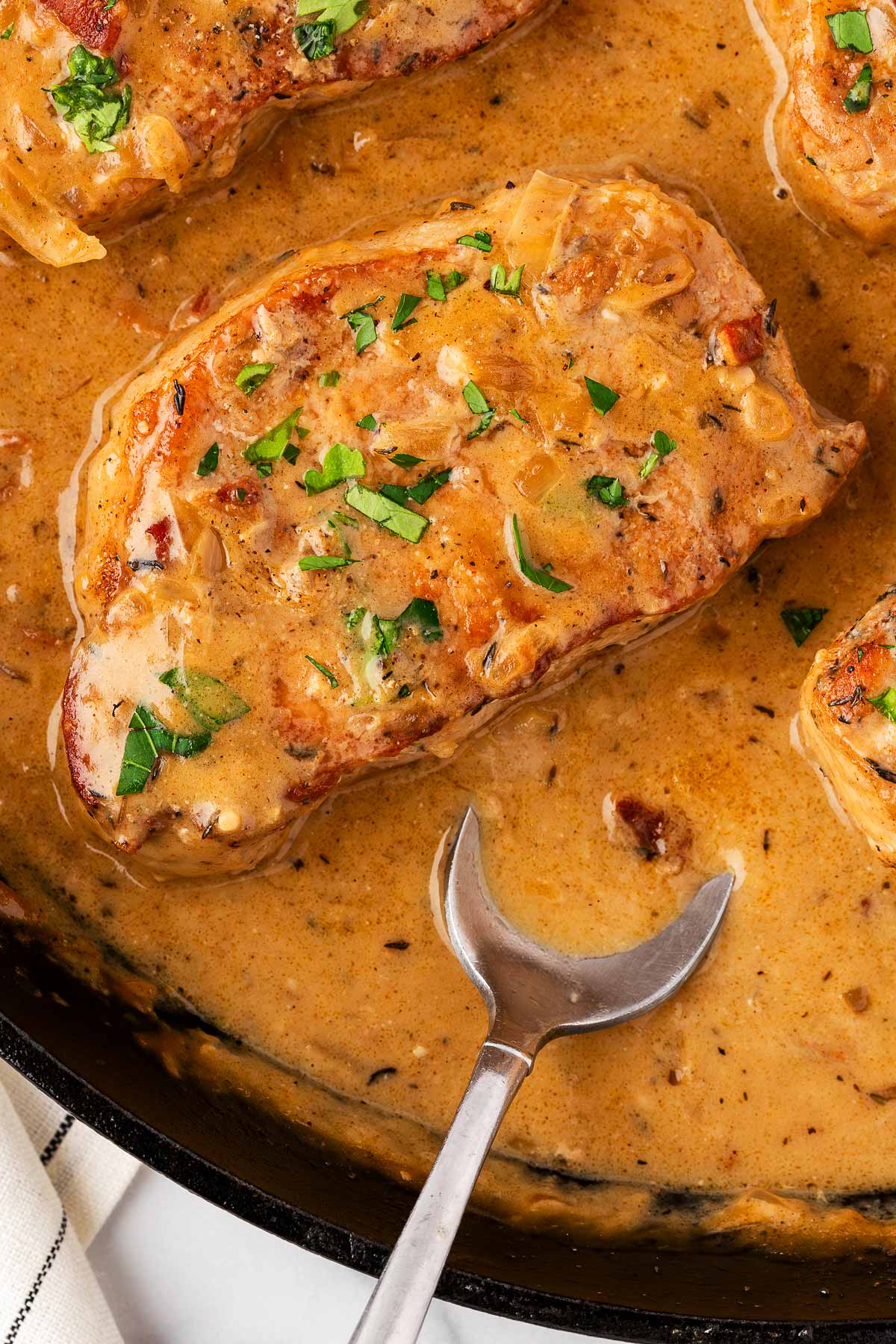 overhead close up view view of pork chop smothered in gravy in cast iron skillet