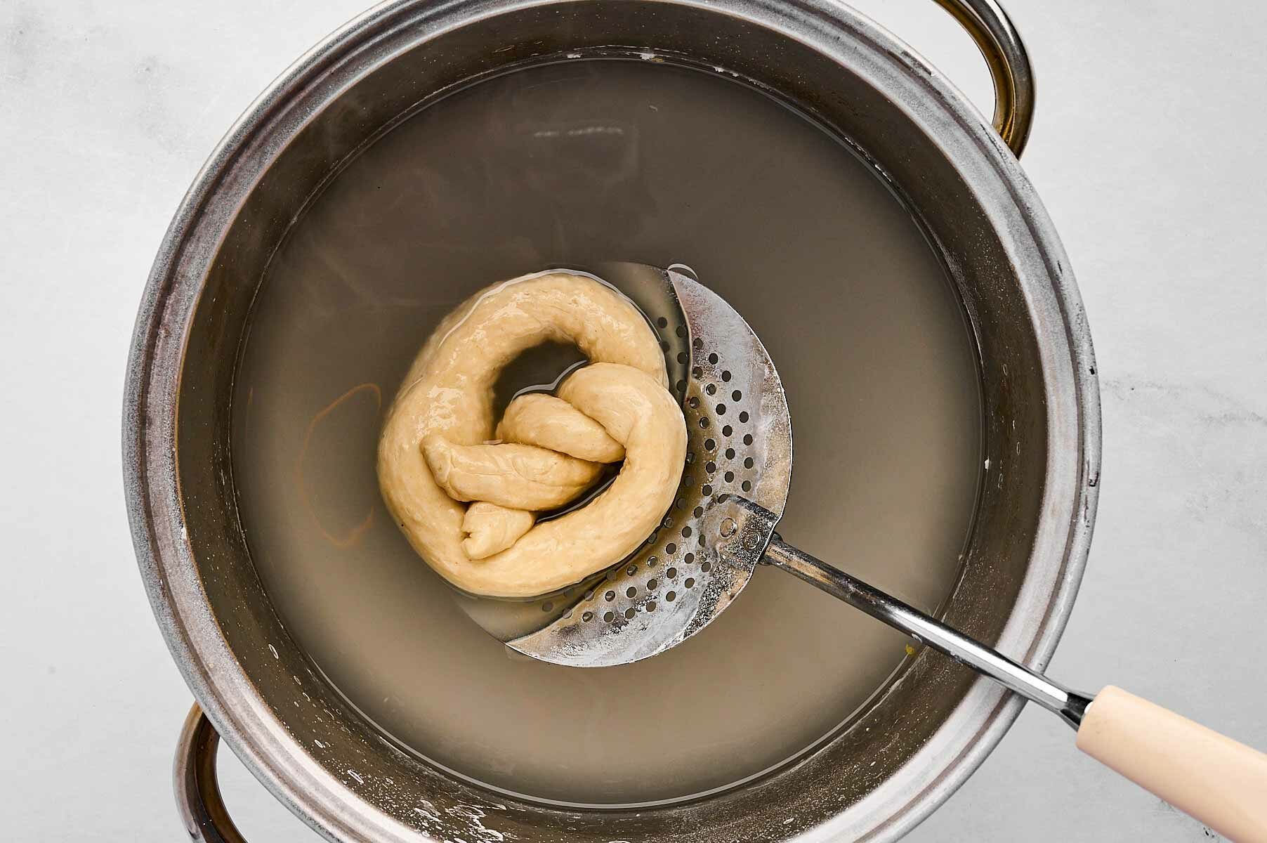 overhead view of pretzel being dipped into brine