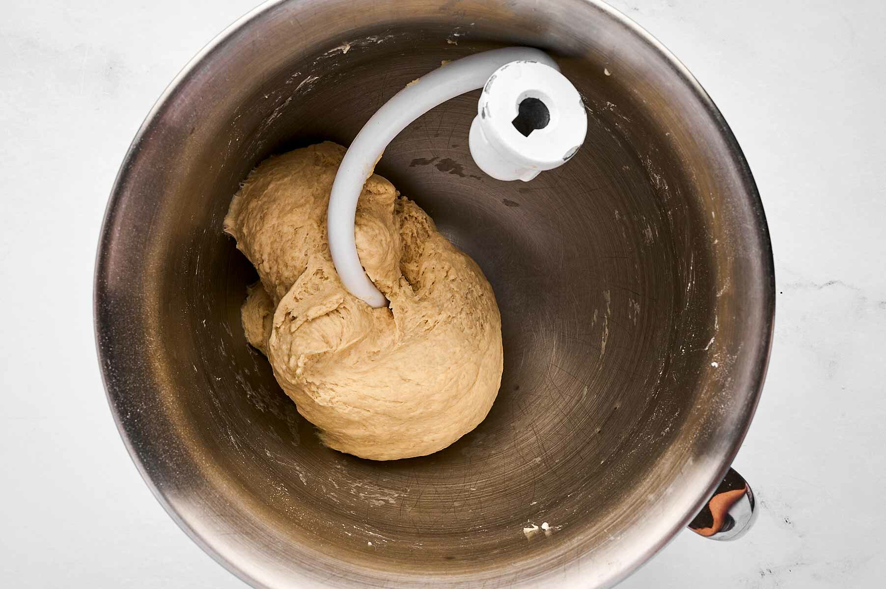 overhead view of kneaded dough in mixer bowl with dough hook