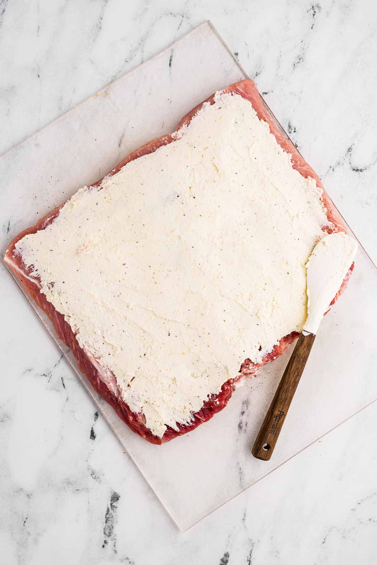 overhead view of butterflied pork loin spread with seasoned cream cheese