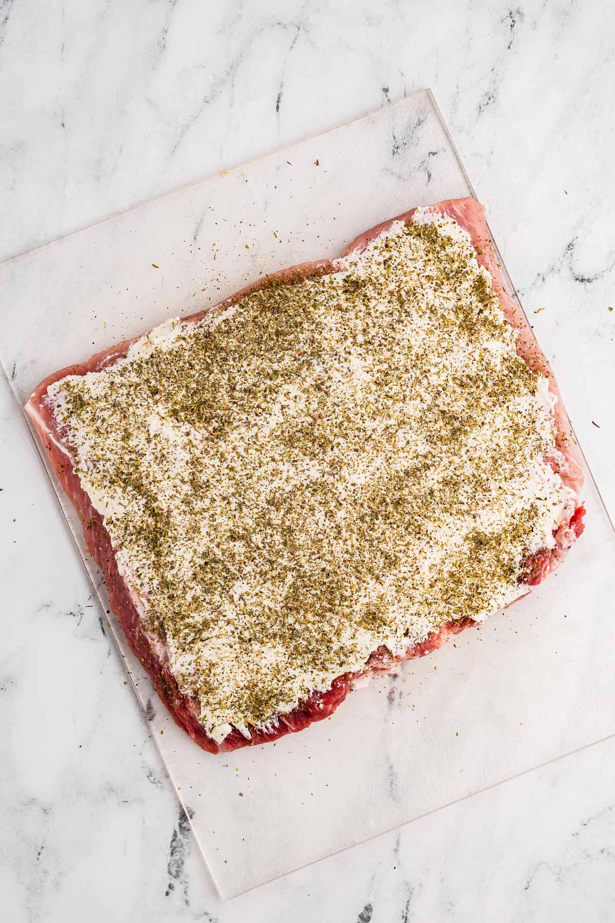 overhead view of butterflied pork loin spread with seasoned cream cheese and seasoning