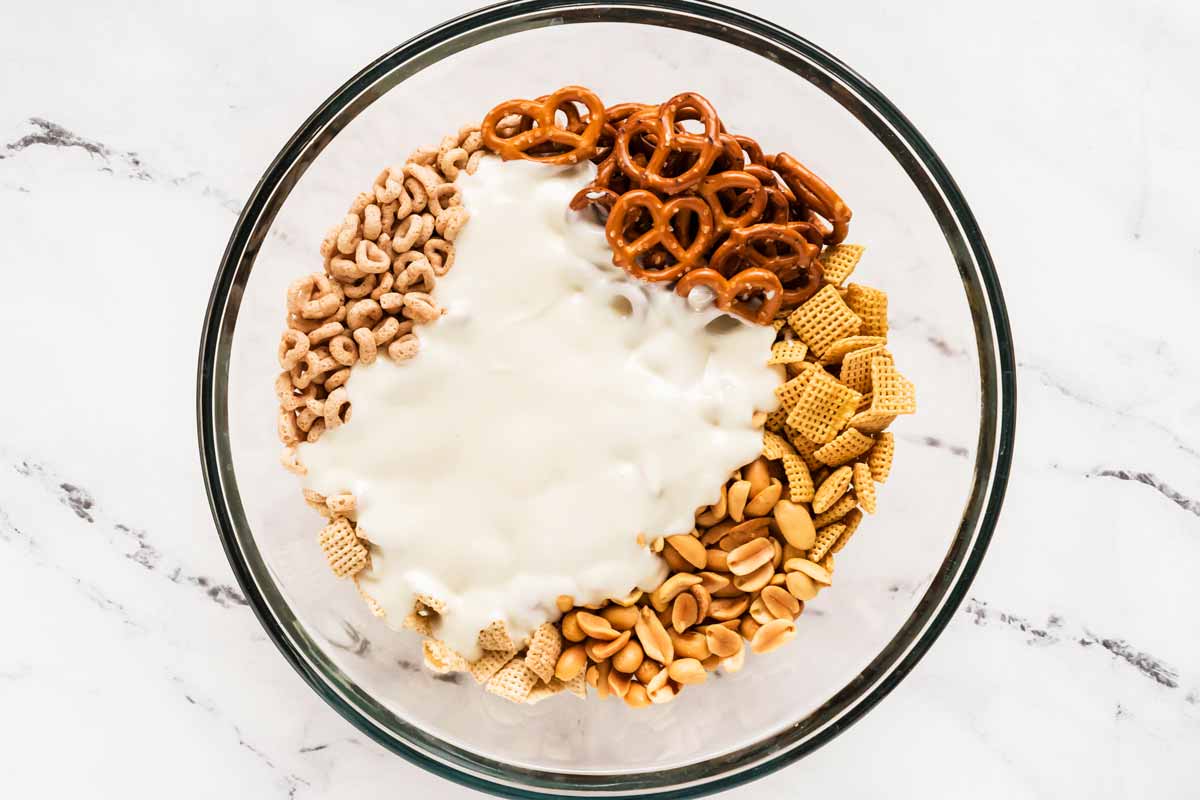 overhead view of dry ingredients for Chex mix in bowl with melted white chocolate