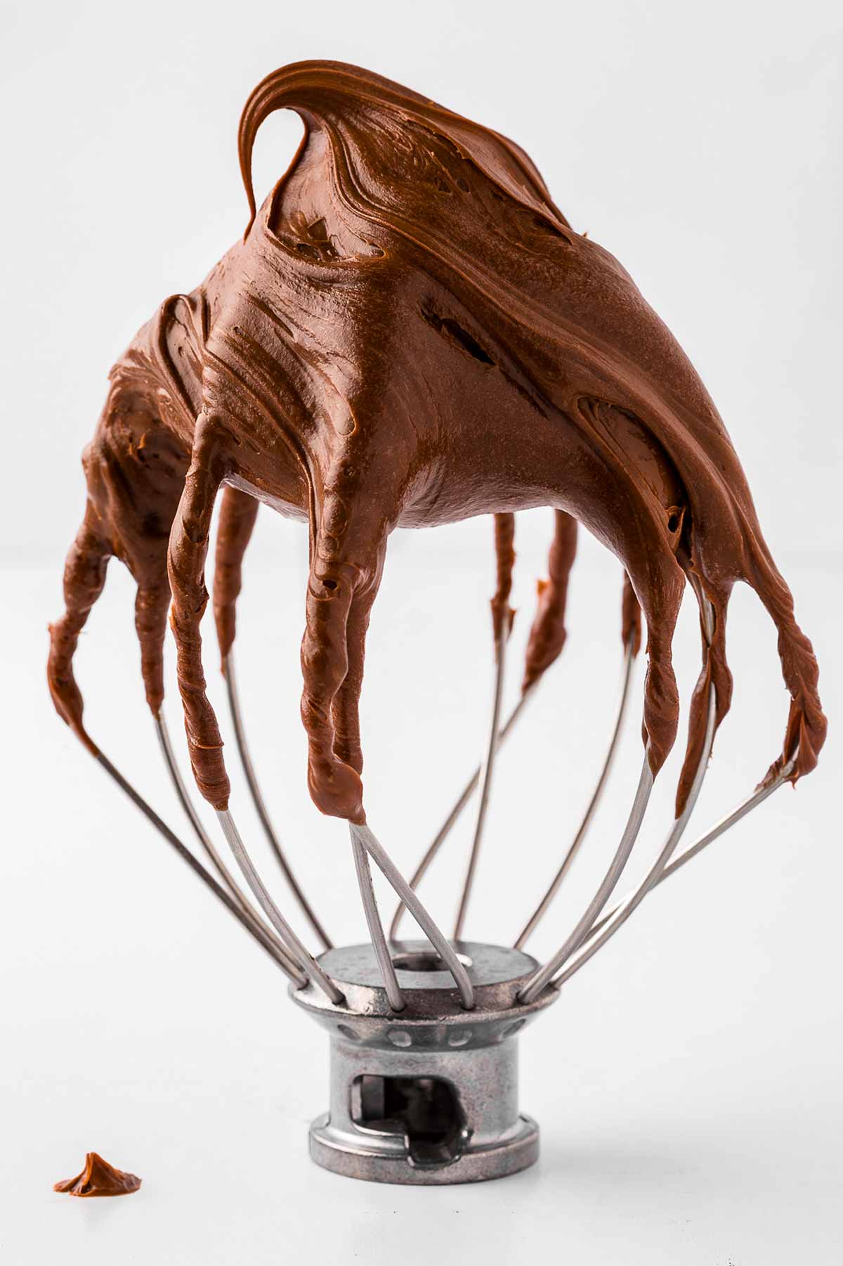 frontal view of mixer whisk attachments full of whipped chocolate ganache