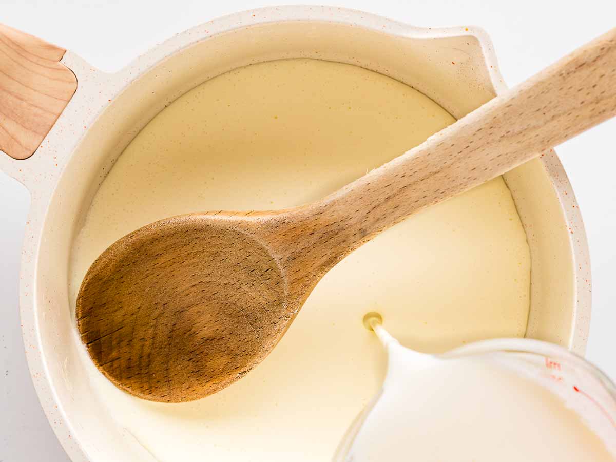 overhead view of cream being added to saucepan