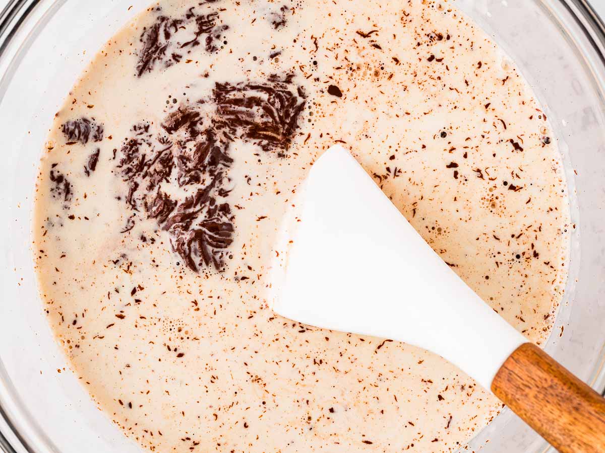 overhead view of hot cream and chopped chocolate in glass bowl