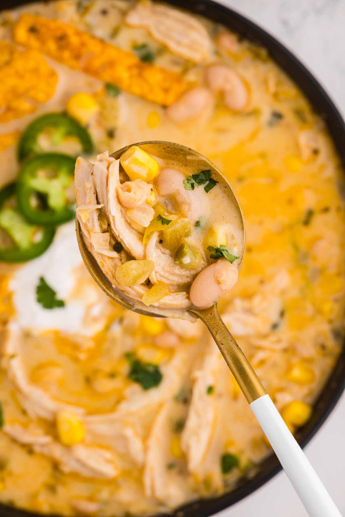 overhead close up view of white chicken chili on spoon