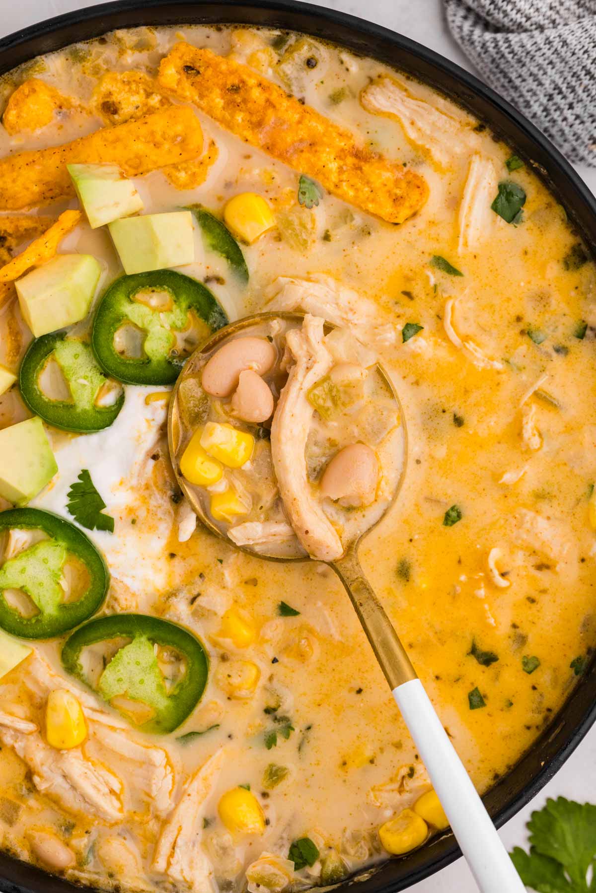 overhead close up view of white chicken chili in bowl with spoon