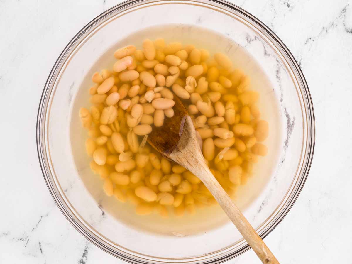 overhead view of white beans and chicken broth in bowl