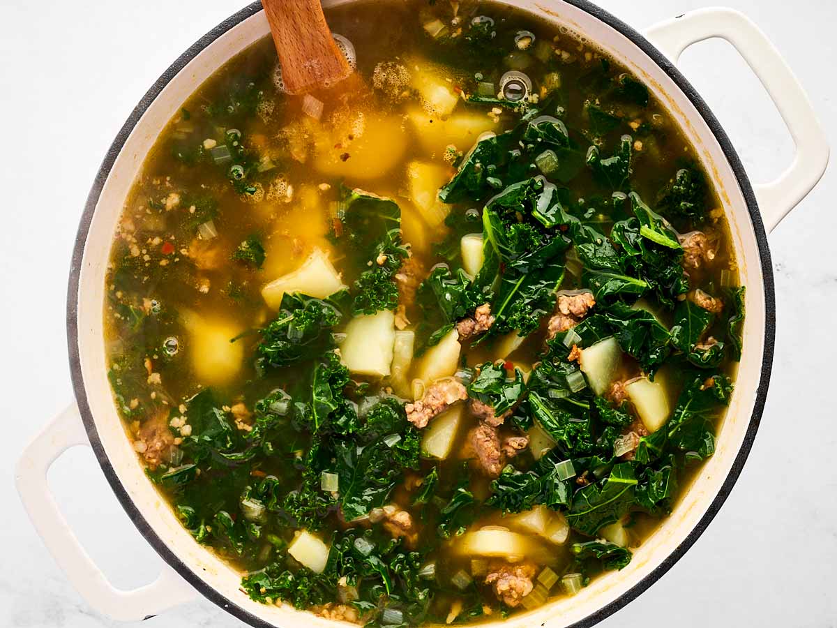 overhead view of cooked potatoes and kale in broth in pot