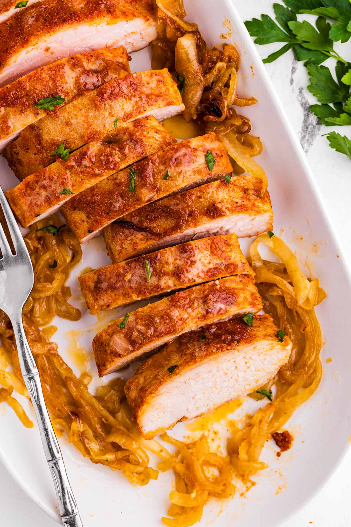 overhead view of sliced baked pork tenderloin in baking dish