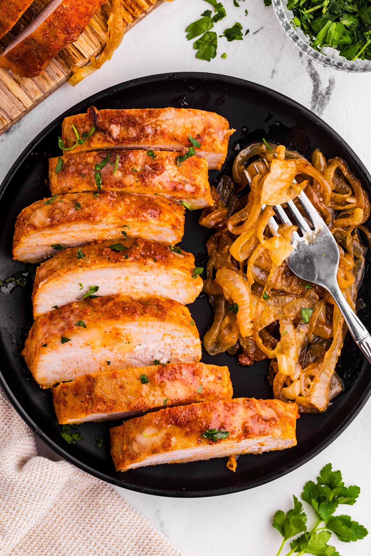 overhead view of sliced pork tenderloin on plate with browned onions