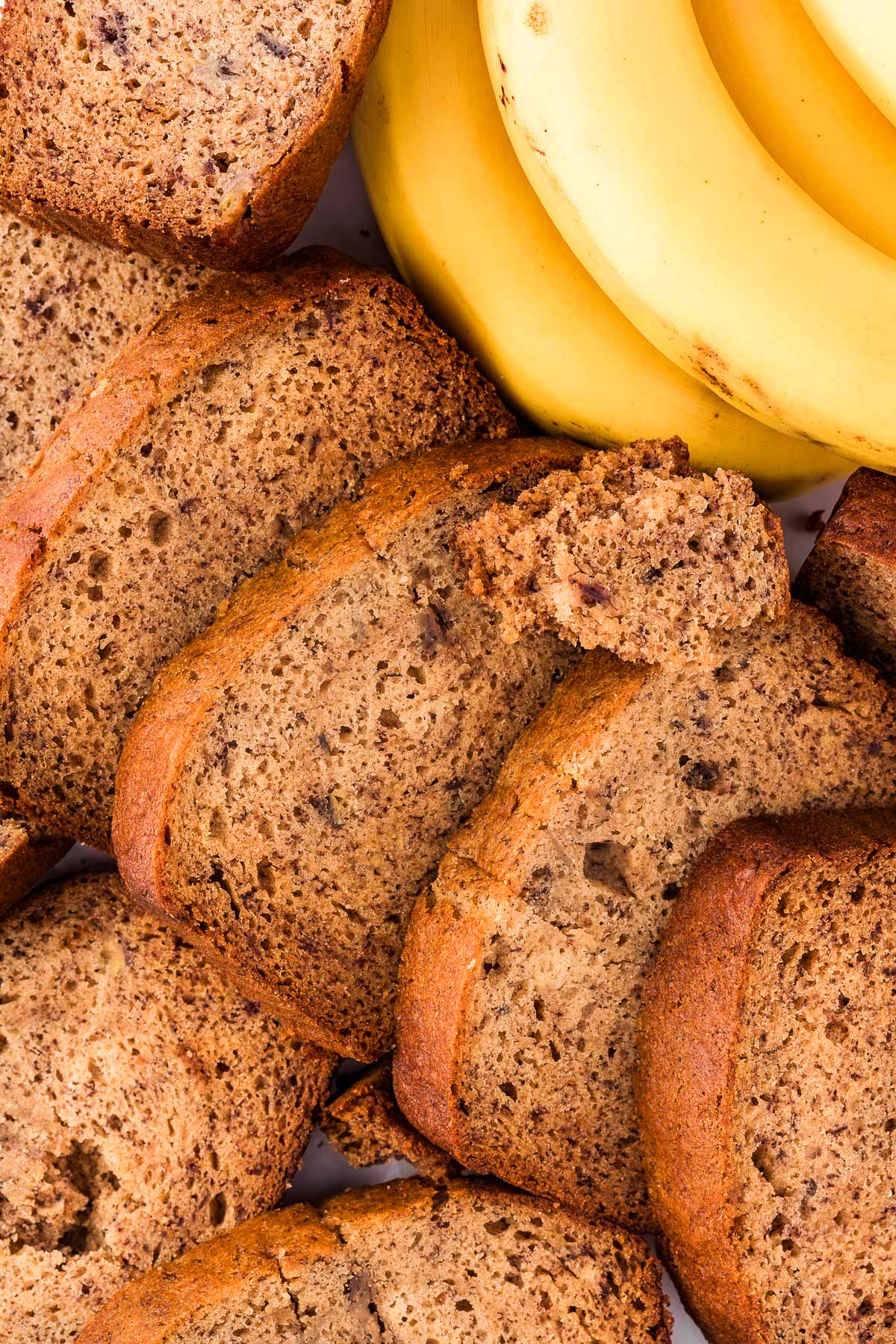 overhead view of sliced banana bread with fresh bananas