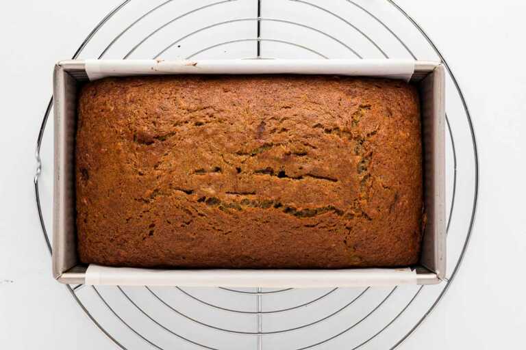 overhead view of baked banana bread in pan on wire rack