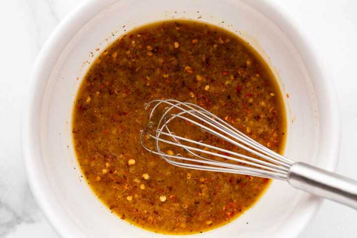 overhead view of stir fry sauce in small white bowl with whisk