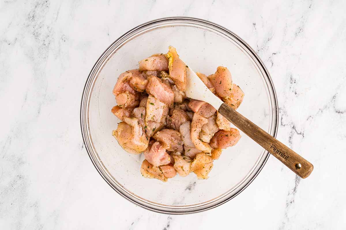 overhead view of seasoned diced chicken breast in glass bowl