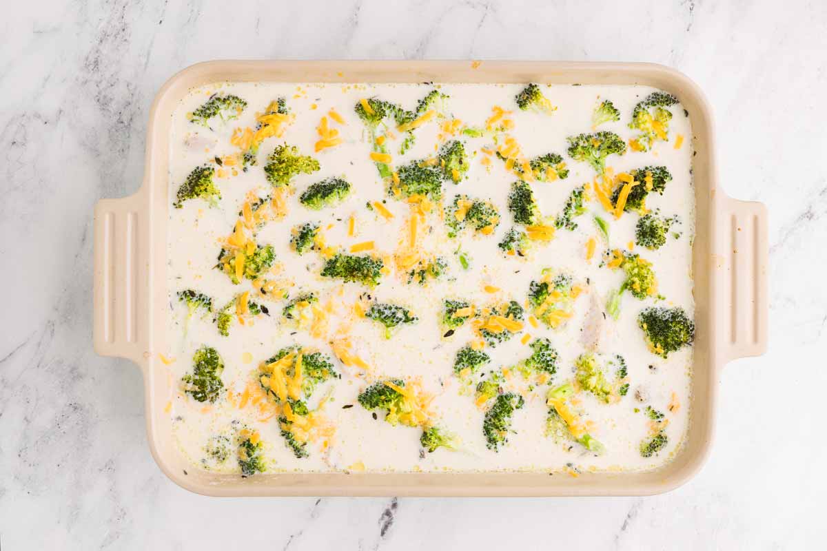 overhead view of half baked chicken broccoli rice casserole with cheese added