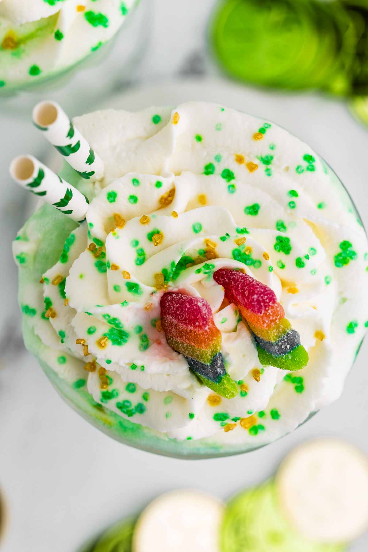 overhead view of shamrock shake decorated with sour rainbow candy and whipped cream