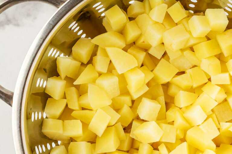 overhead view of parboiled potato cubes in colander