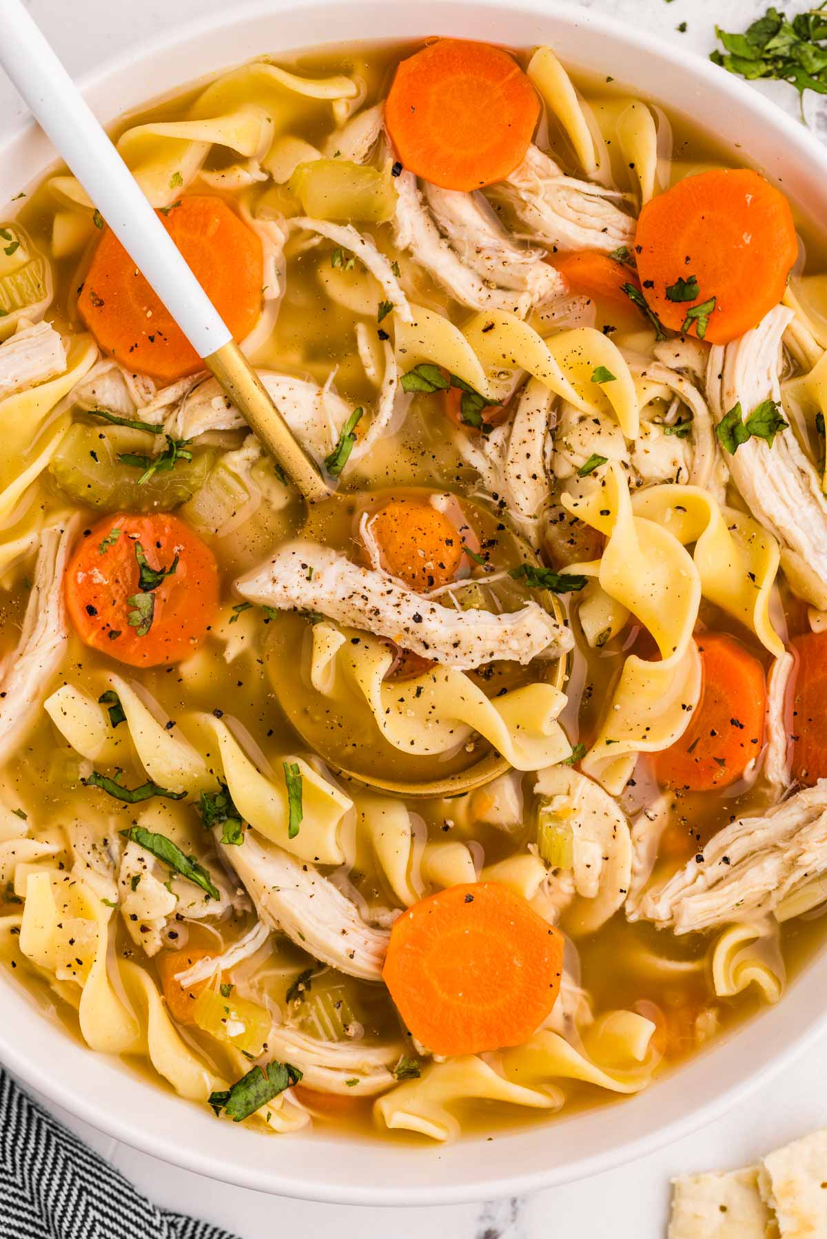 overhead close up view of chicken noodle soup in white bowl