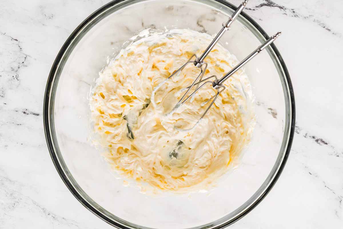 overhead view of hand mixer beaters in bowl with cream cheese