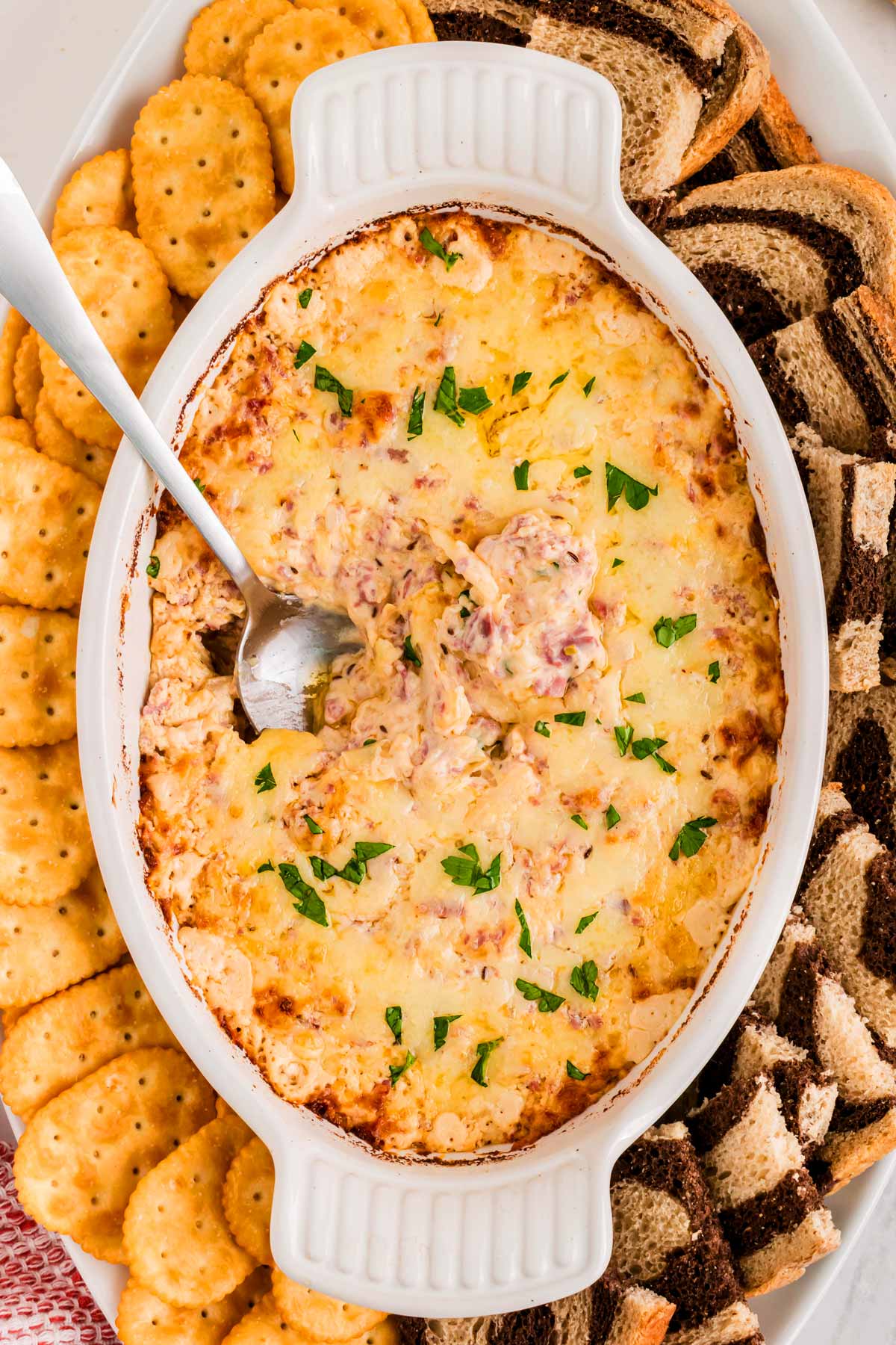 overhead view of hot reuben dip in white baking dish with spoon stuck in