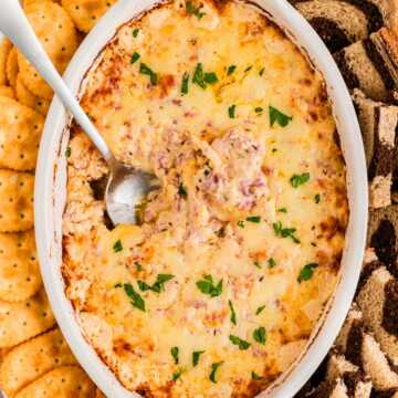 overhead view of hot reuben dip in white baking dish with spoon stuck in