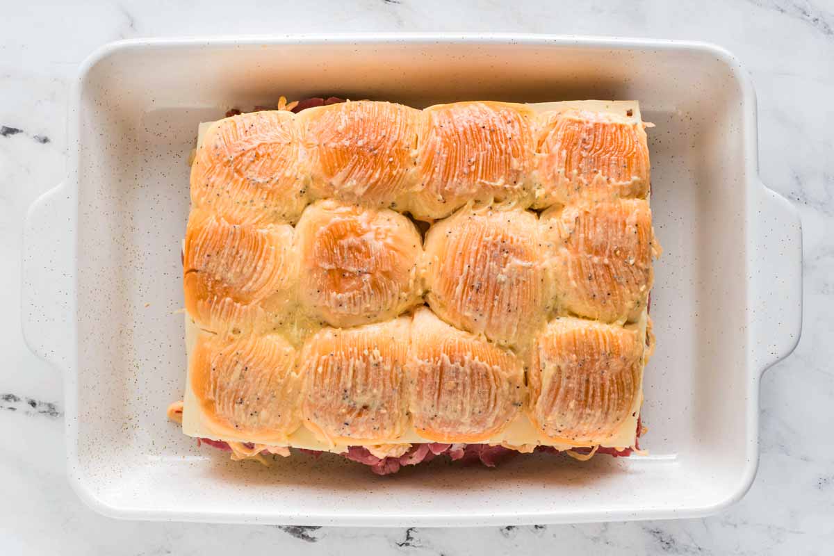 overhead view of dinner rolls brushed with melted butter in casserole dish