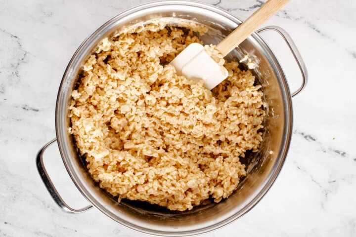 overhead view of melted marshmallows in pot stirred together with Rice Krispie cereal