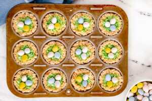 overhead view of muffin pan filled with decorated Rice Krispie "easter nests"