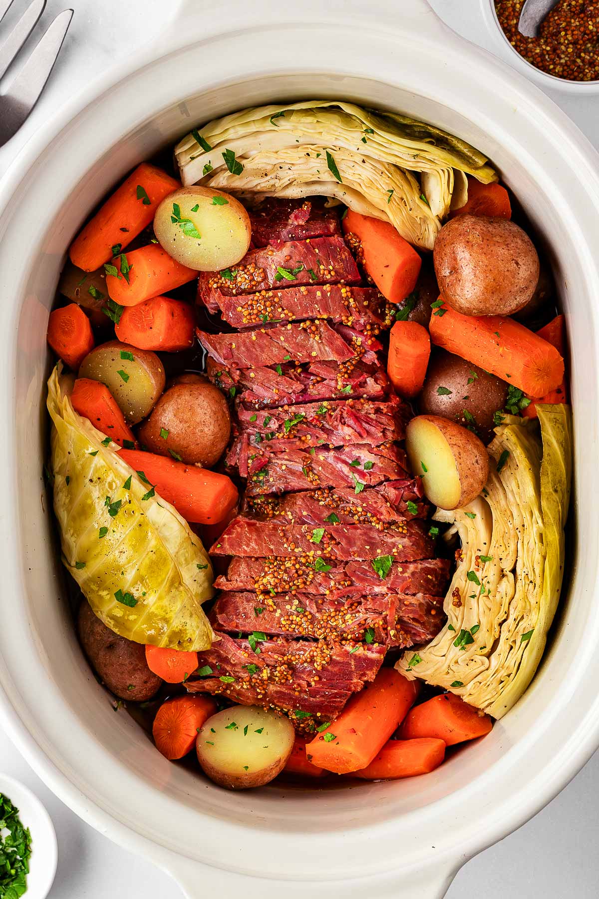 overhead close up view of corned beef, cabbage and vegetables in slow cooker insert