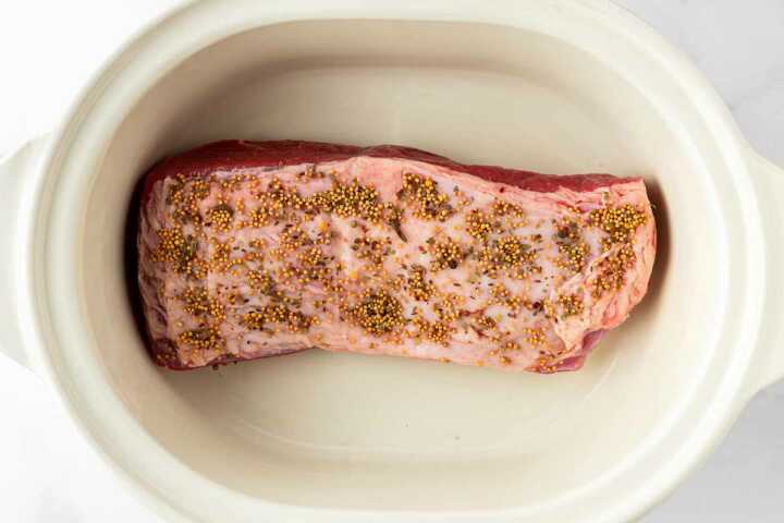 overhead view of uncooked corned beef brisket in slow cooker