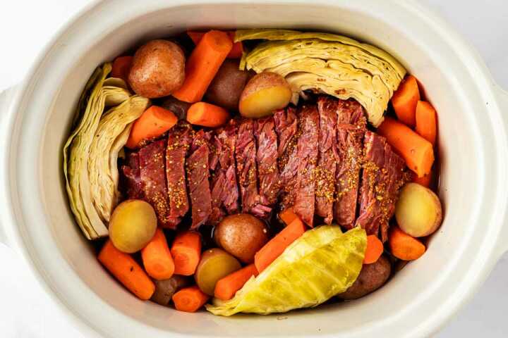 overhead view of corned beef, cabbage and vegetables in slow cooker insert