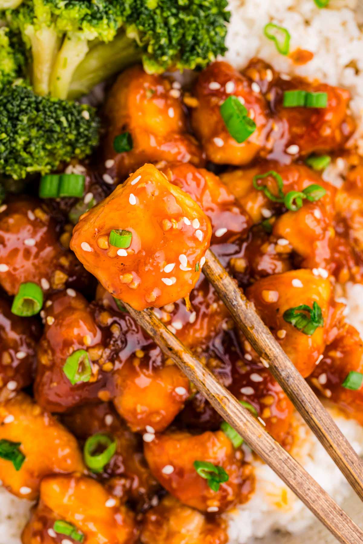 overhead view of chopsticks holding piece of teriyaki chicken