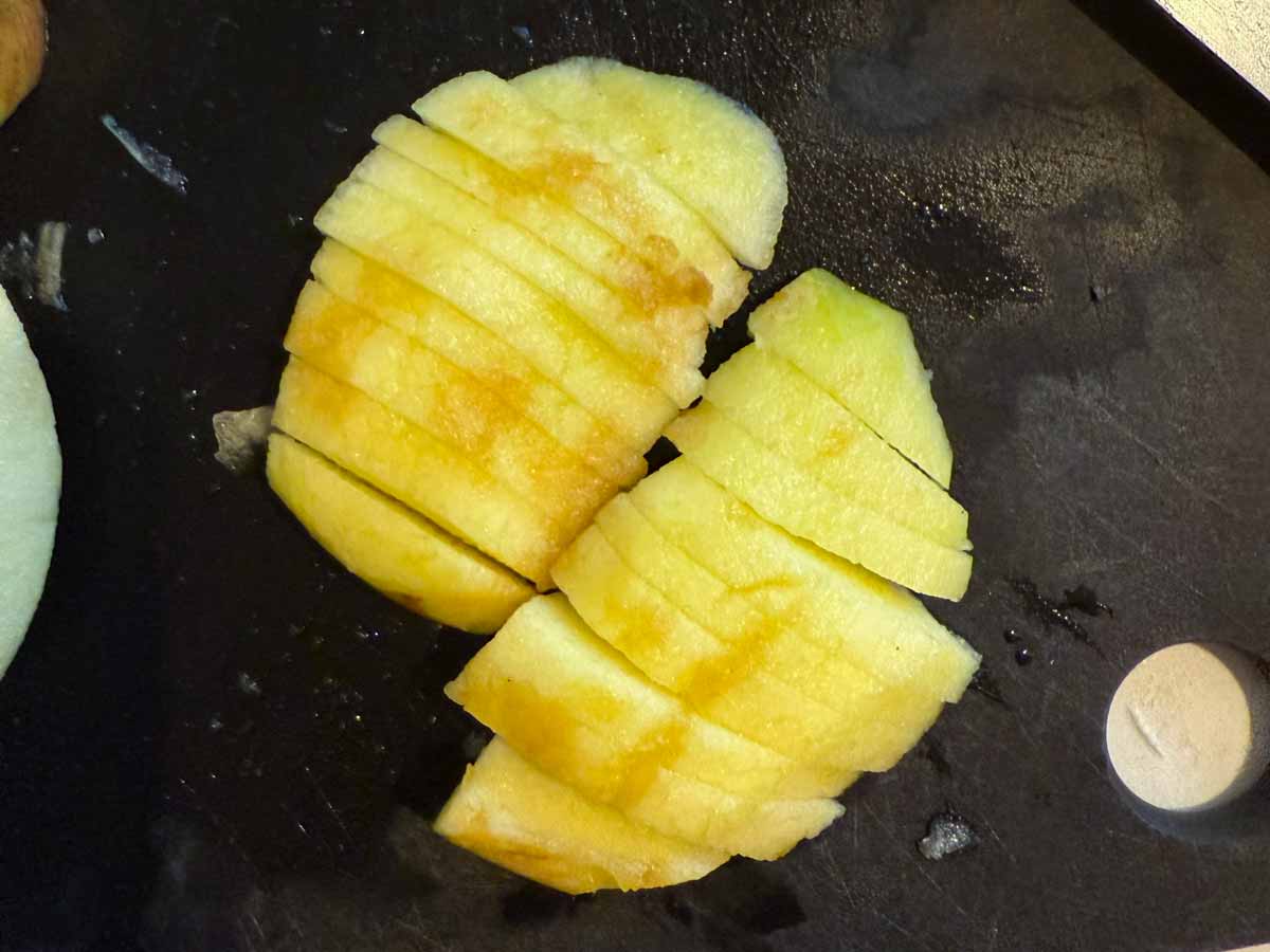 overhead view of sliced apples on black cutting board