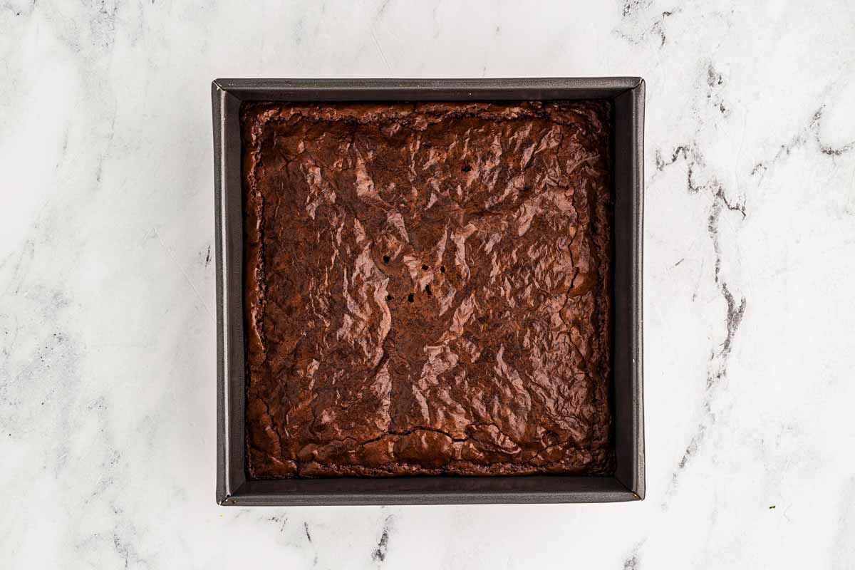 Baked brownie base cooling in a square pan before frosting