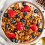 overhead view of peanut butter granola in bowl with milk and berries