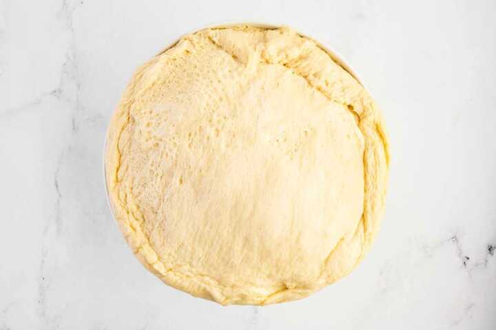 overhead view of risen potato roll dough in bowl